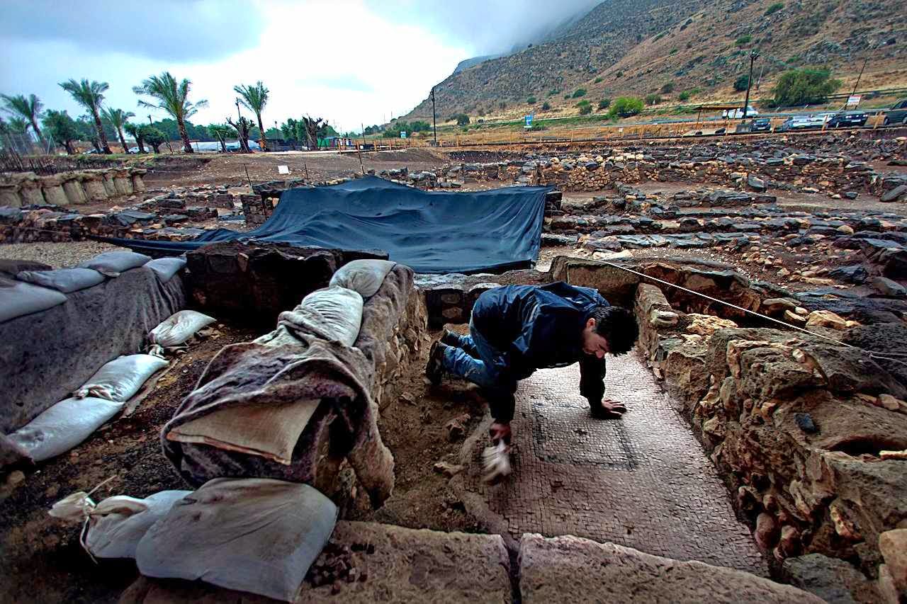 Funcionário limpa mosaicos ornamentados no sítio arqueológico de Migdal, Israel